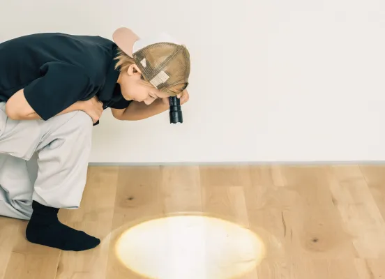 異物の混入がないかを床にライトを当てて確認しているスタッフ